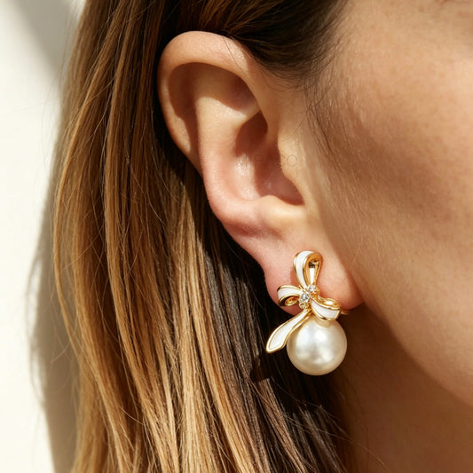 Close-up of an ear wearing a gold and pearl earring with a neutral background