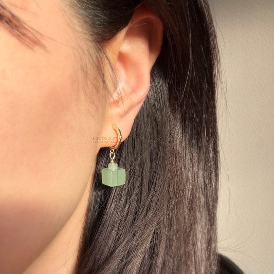 Small Gold Hoops with Square Jade Look Gem | Handmade Coil Clip Earrings for Non-Pierced Ears
A touch of green, a hint of gold – all without the need for pierced ears.
These elegant clip-on earrings feature delicate gold-toned hoops paired with a striking green stone cube dangle. The semi-translucent stone resembles green aventurine, with a gentle, jade-like appearance that catches the light beautifully.
Note:
Each stone is natural and unique, so slight variations in tone and texture may occur – a lovely