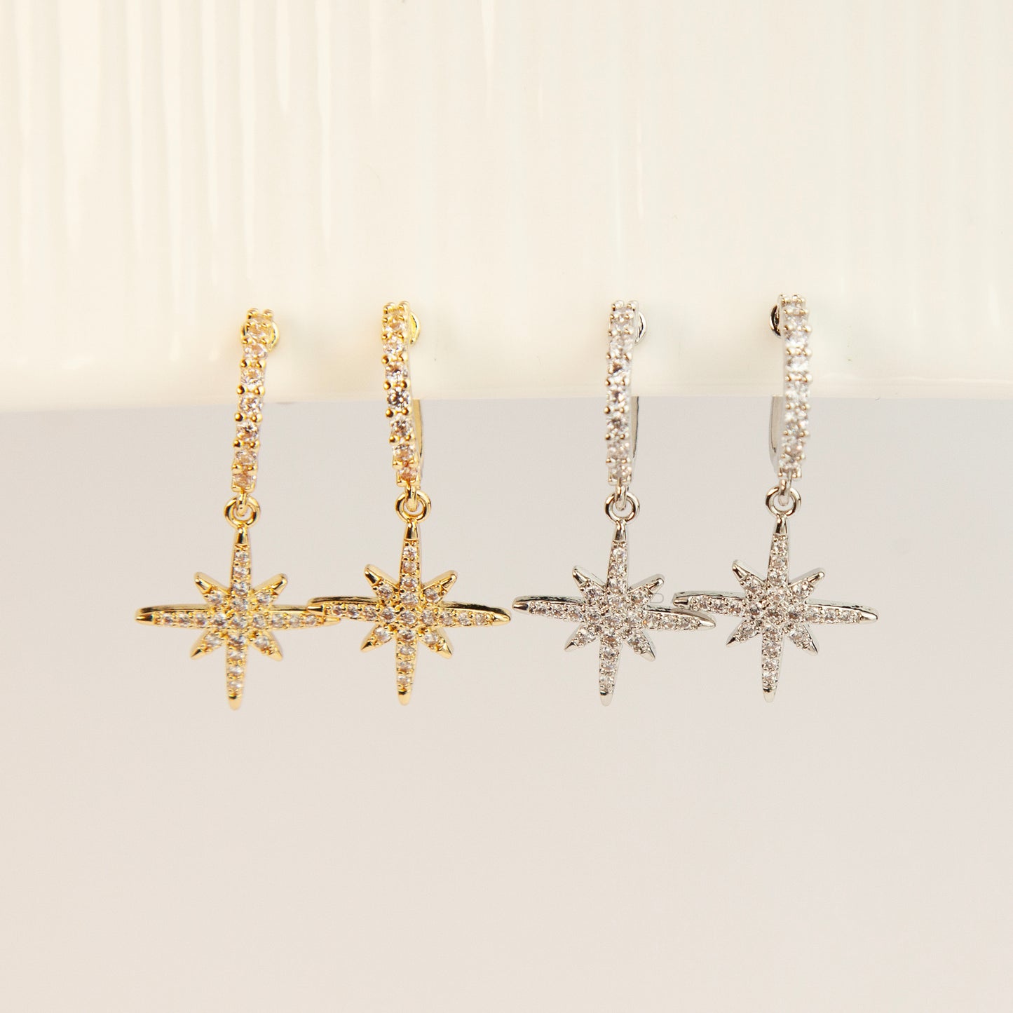 Gold and silver non-pierced clip-on dangle earrings with coil backs, featuring cubic zirconia paved hoops and celestial starburst drops.