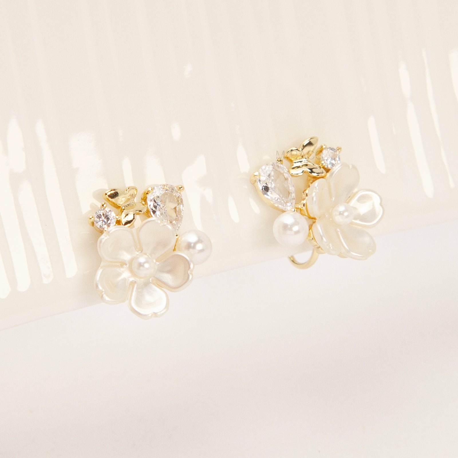 Gold-tone pearl flower clip-on earrings with crystals and coil-back clips for non-pierced ears.