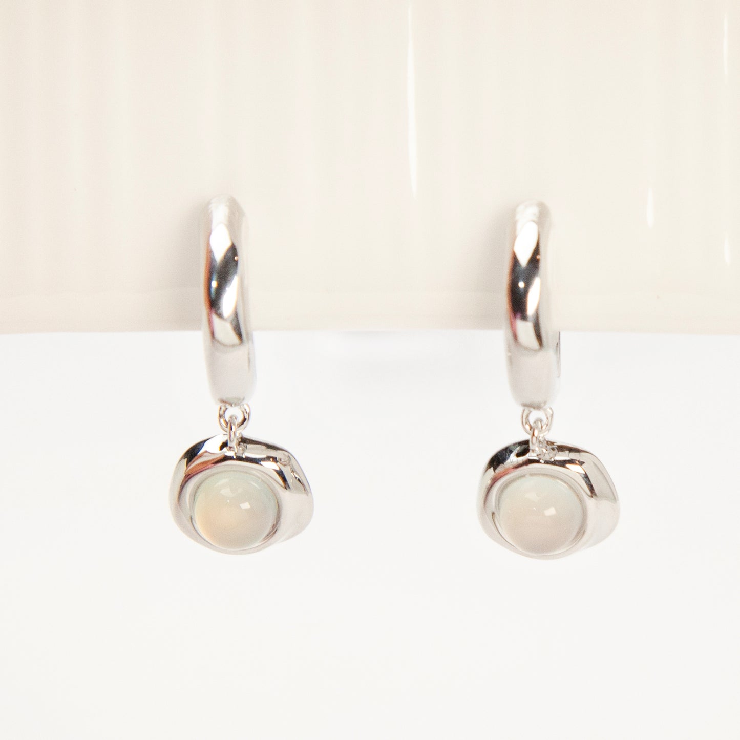 Silver opal-style clip-on earrings with curved modern design and coil-back clips for non-pierced ears.