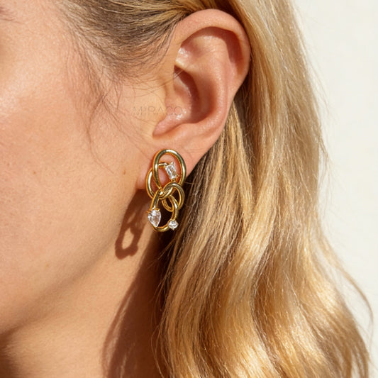 Model wearing a single gold interlocking double-knot clip-on earring with CZ stones, showing the size and fit on a non-pierced ear.