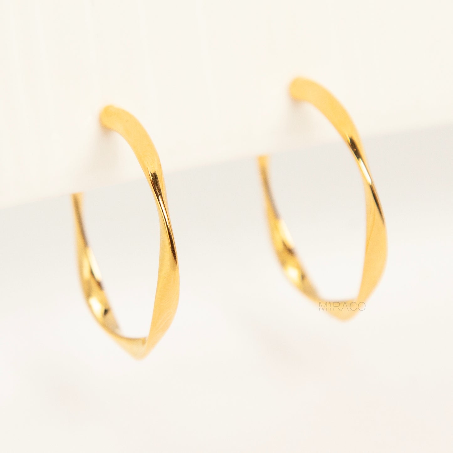 Pair of polished gold twisted hoop clip-on earrings with adjustable screw-back closures