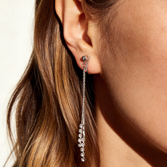 Pair of silver double-strand linear drop clip-on earrings with crystal tips and adjustable screw-back closures on a white background.