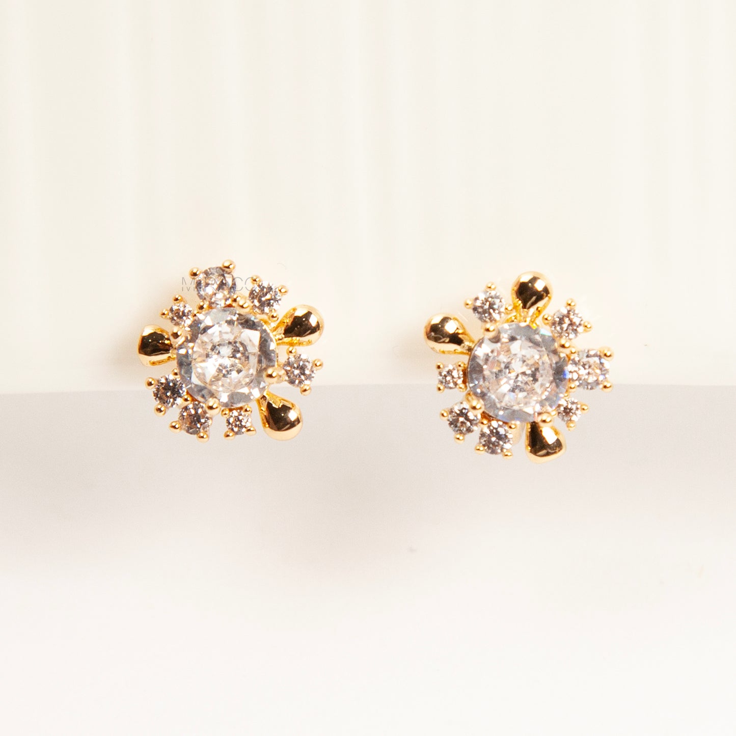 Pair of gold-tone sunburst-shaped clip-on earrings with a central cubic zirconia stone and comfortable invisible coil back closures.