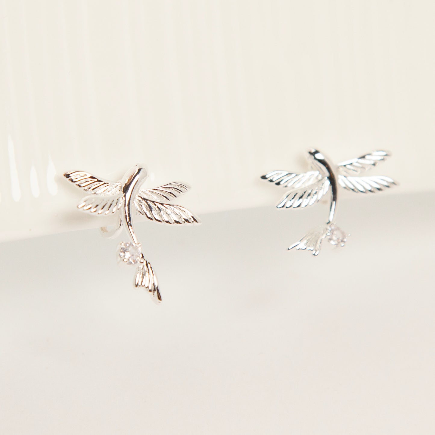 Pair of silver-tone bird-shaped clip-on earrings in flight with clear crystals and comfortable invisible coil back closures.