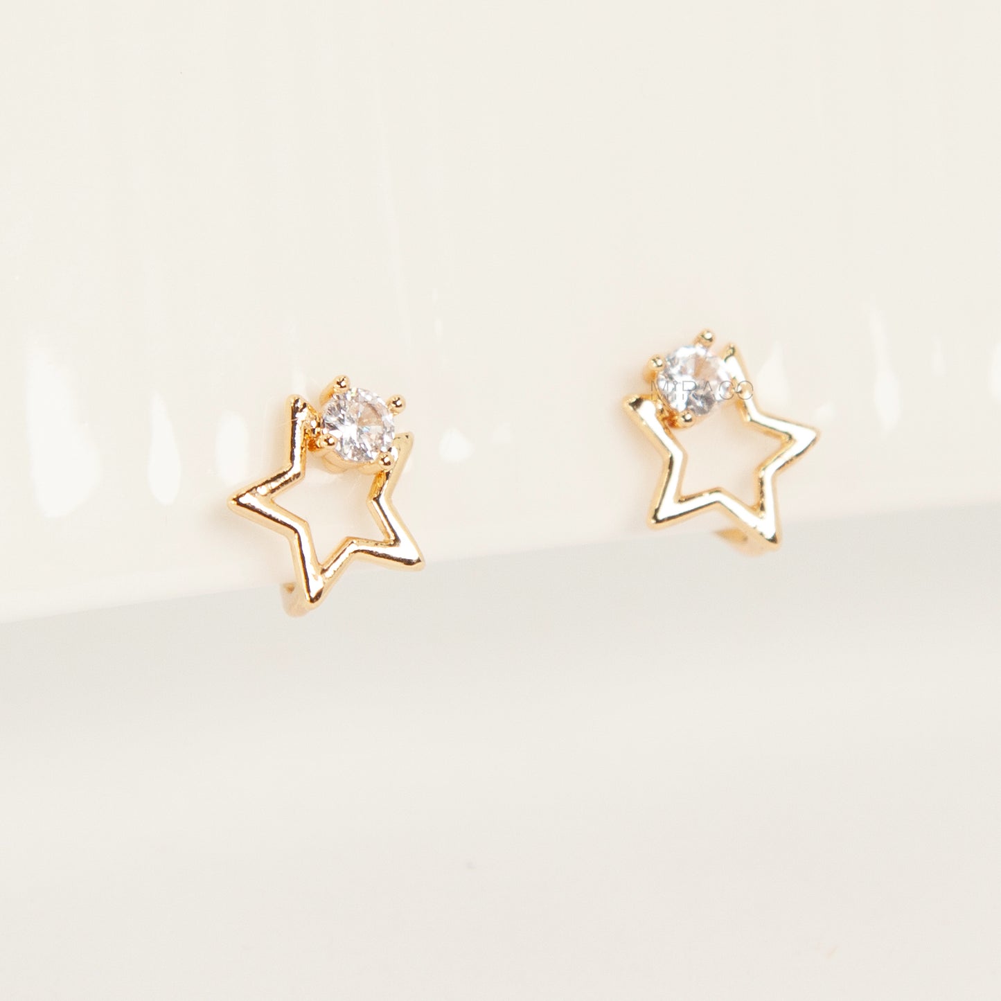 Pair of gold-tone open star-shaped clip-on earrings featuring a small clear crystal and comfortable invisible coil back closures.