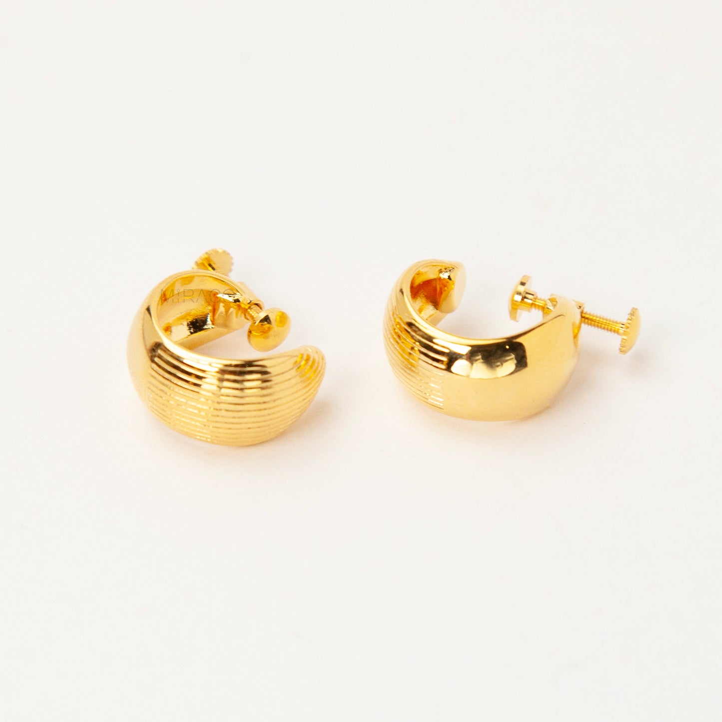 A pair of chunky, polished gold-tone dome clip-on earrings featuring a textured ribbed pattern and adjustable gold screw-back fasteners for non-pierced ears.