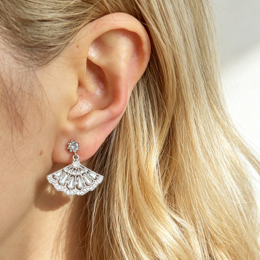 A pair of silver-tone Art Deco style clip-on drop earrings featuring a fan-shaped design set with baguette and round clear crystals, with adjustable coil-spring backs.