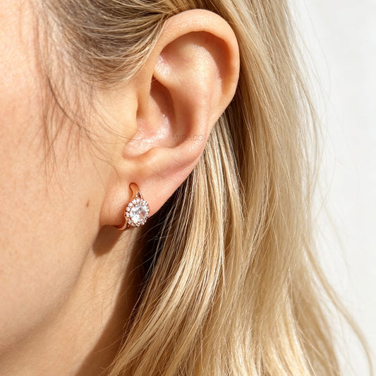 Gold and silver halo crystal coil-back clip-on huggie earrings set with a round solitaire gem surrounded by pave stones.