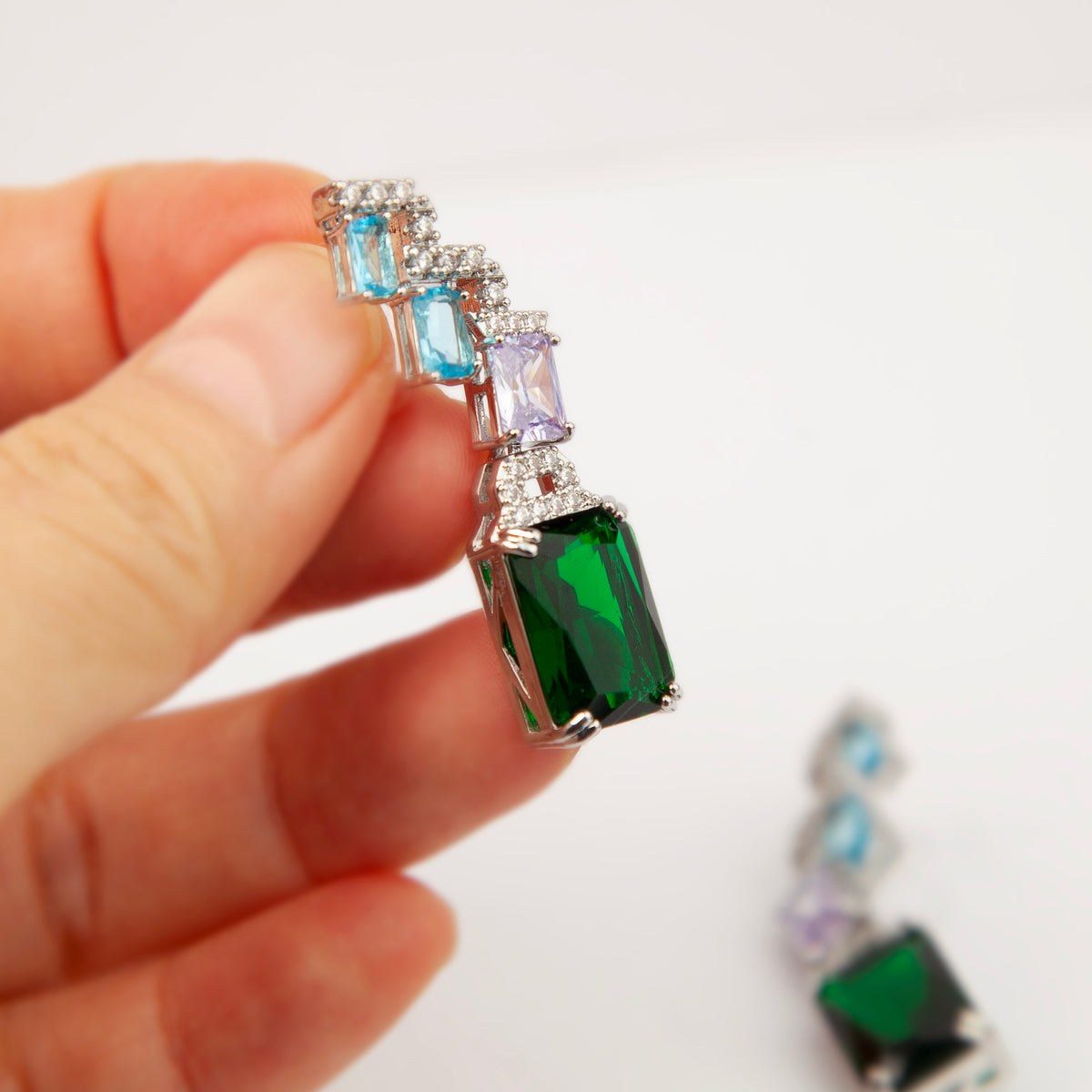 Art deco style multicolor clip-on drop earrings with blue, purple, and green emerald-cut crystals and invisible clear backs.