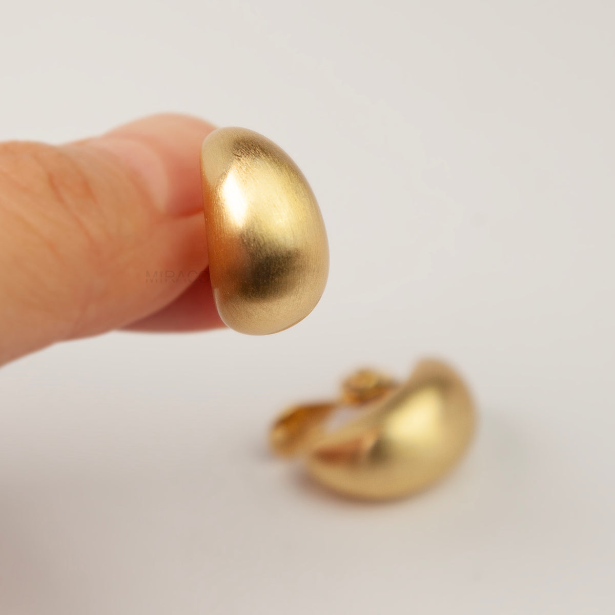 brushed matte gold curved dome huggie clip-on earrings with paddle clip back closure for unpierced ears.