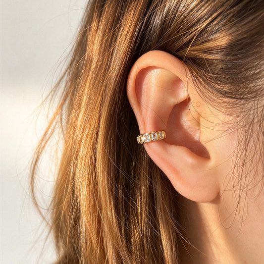 Woman wearing an 18K gold-plated stainless steel non-pierced ear cuff set with emerald-cut baguette cubic zirconia on her outer ear cartilage.