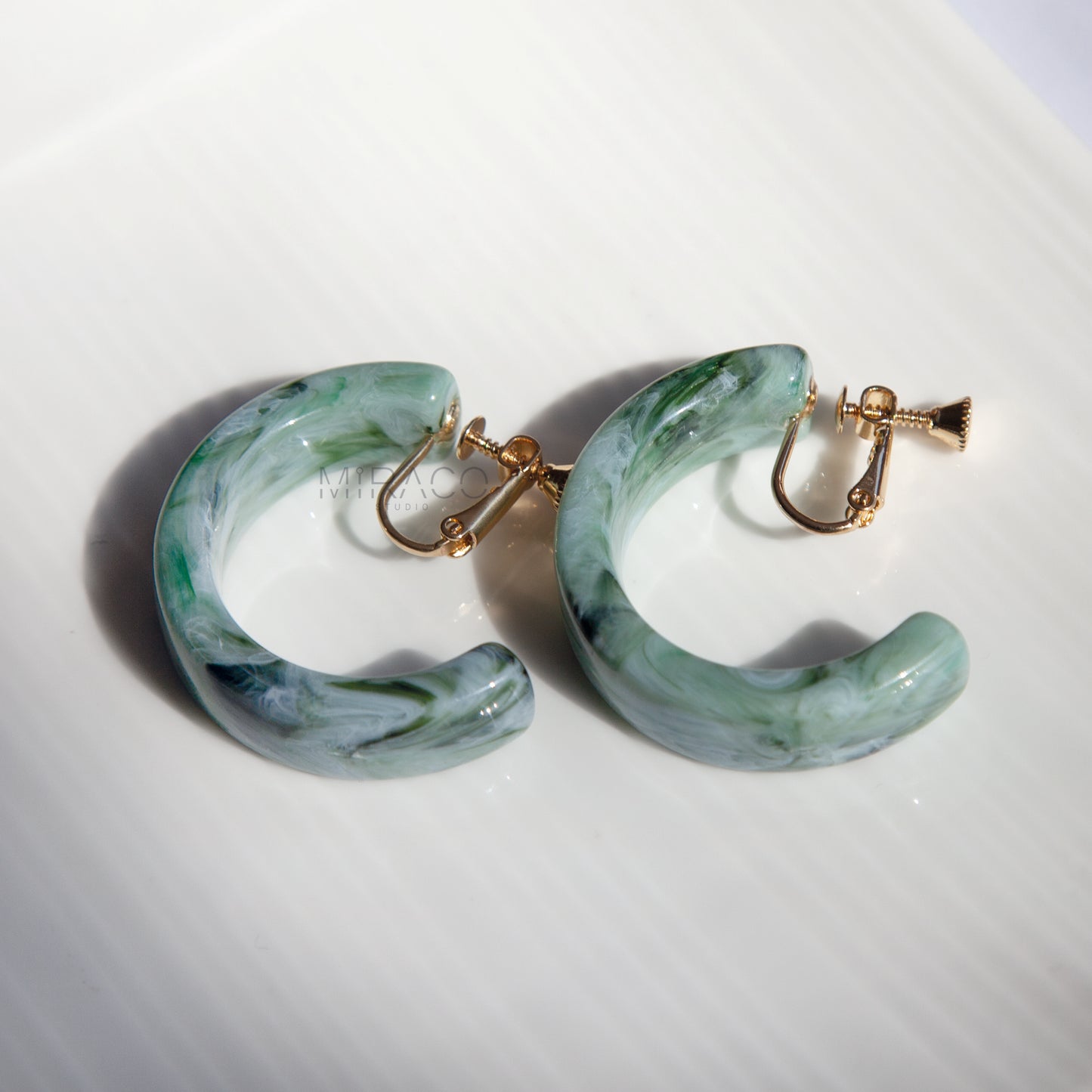 o Bold with Statement Hoops. Make a confident style statement with these eye-catching large hoop earrings, designed for ultimate comfort without piercings. Featuring a substantial 40mm diameter, these hoops command attention with their beautiful marbled resin finish. Each pair boasts unique, swirling patterns, available in two gorgeous colorways: a captivating Jade Swirl green and a warmAmber Tortoise brown/orange.