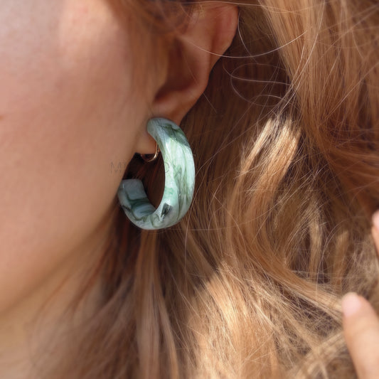 o Bold with Statement Hoops. Make a confident style statement with these eye-catching large hoop earrings, designed for ultimate comfort without piercings. Featuring a substantial 40mm diameter, these hoops command attention with their beautiful marbled resin finish. Each pair boasts unique, swirling patterns, available in two gorgeous colorways: a captivating Jade Swirl green and a warmAmber Tortoise brown/orange.