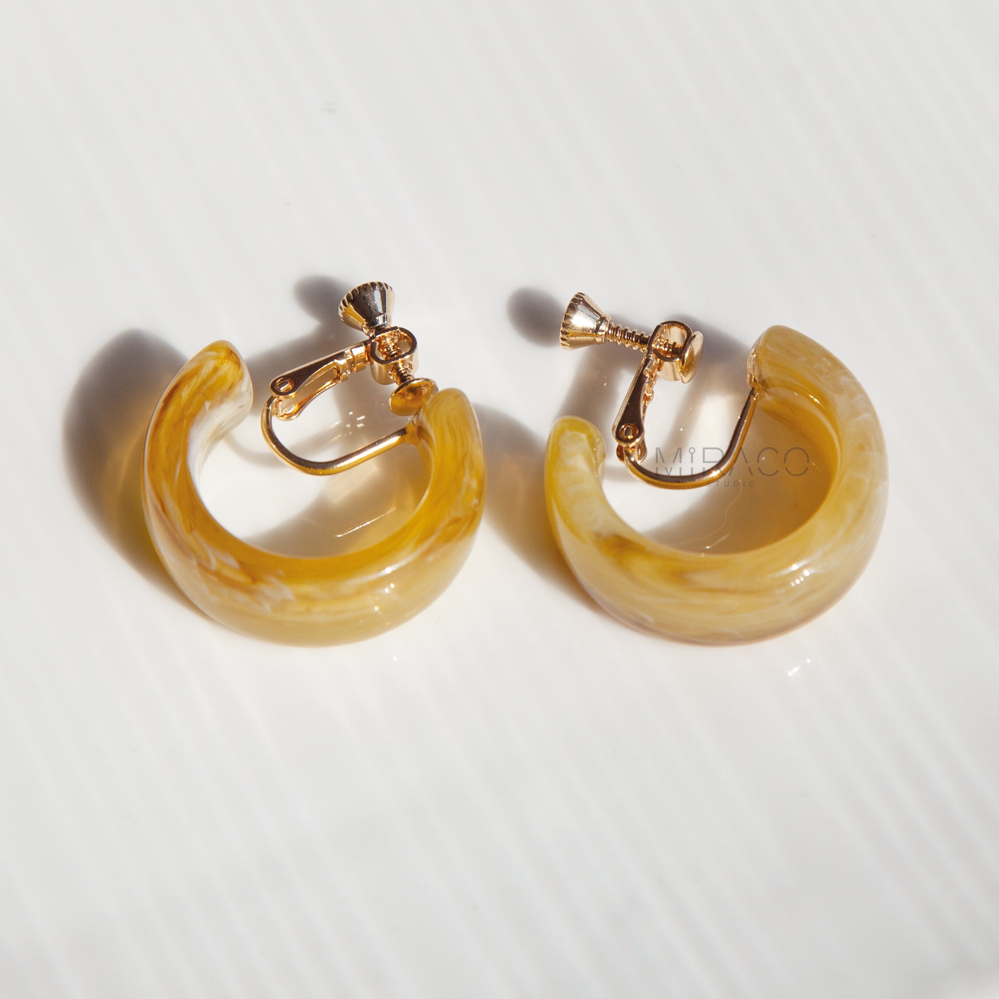 Classic Hoops, Modern Comfort – No Piercing Required! Get the timeless appeal of hoop earrings with the ultimate convenience of clip-ons! These eye-catching hoops are crafted from beautifully marbled resin, featuring unique swirls of color that add a touch of artistic flair to any outfit. Available in two chic colorways –&nbsp;Amber Swirl and&nbsp;Cream Swirl – they offer versatile style options.