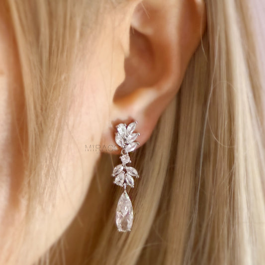 Make a Statement Without the Piercing.

Designed to dazzle, these clip-on dangle earrings feature a cascading leaf-inspired design adorned with sparkling clear cubic zirconia crystals. Long and elegant, they offer that bold, statement look — with mini-clip fastenings that stay secure without pierced ears.

Whether you’re dressing up for a wedding, evening event, or adding glamour to your everyday style, these earrings bring graceful movement and eye-catching shine.