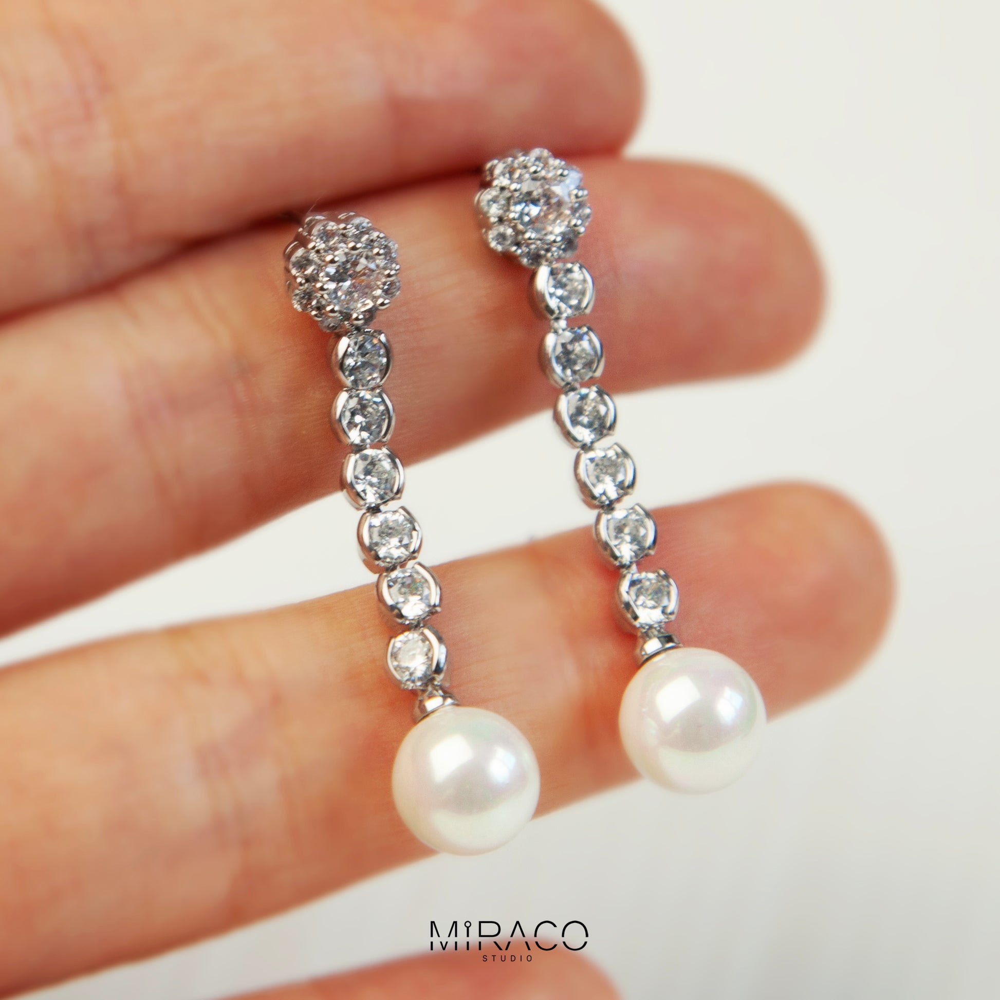 Pair of long dangle clip-on earrings with Mini-Clip back, featuring a paved CZ top and spherical pearl drop