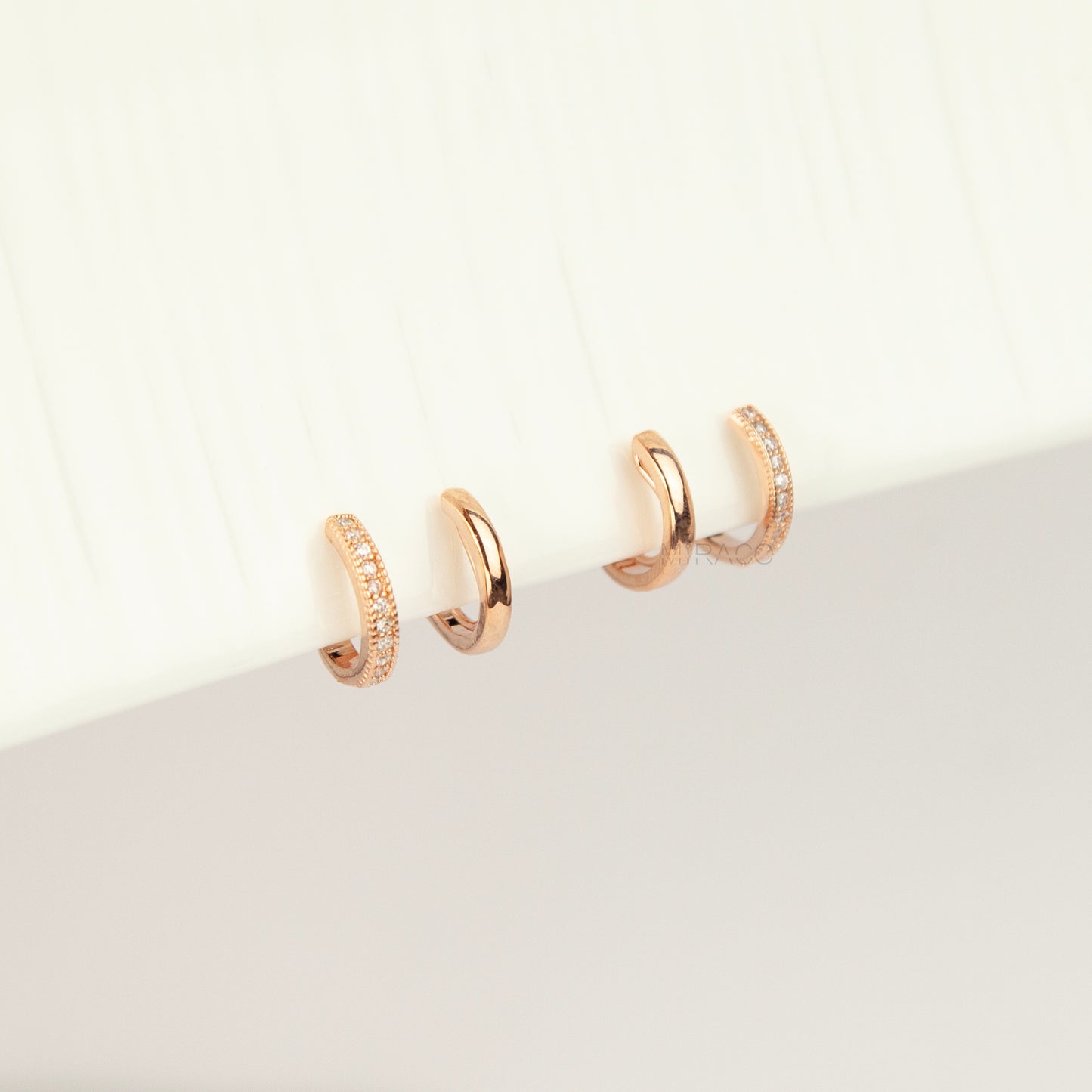 Pair of rose gold non-pierced double band clip-on hoop earrings with pavé cubic zirconia accents and clear silicone spiral coil backs.