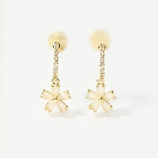A pair of gold-tone drop clip-on earrings featuring a vertical bar set with small clear crystals and a dangling five-petal flower with opalescent stones, equipped with adjustable coil-spring backs.