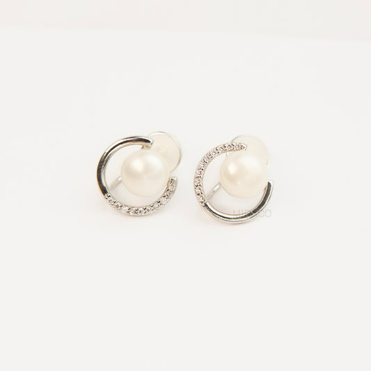 Pair of non-pierced silver-tone clip-on earrings with round silicone backs, featuring a real white freshwater pearl wrapped in a sparkling cubic zirconia crescent loop.