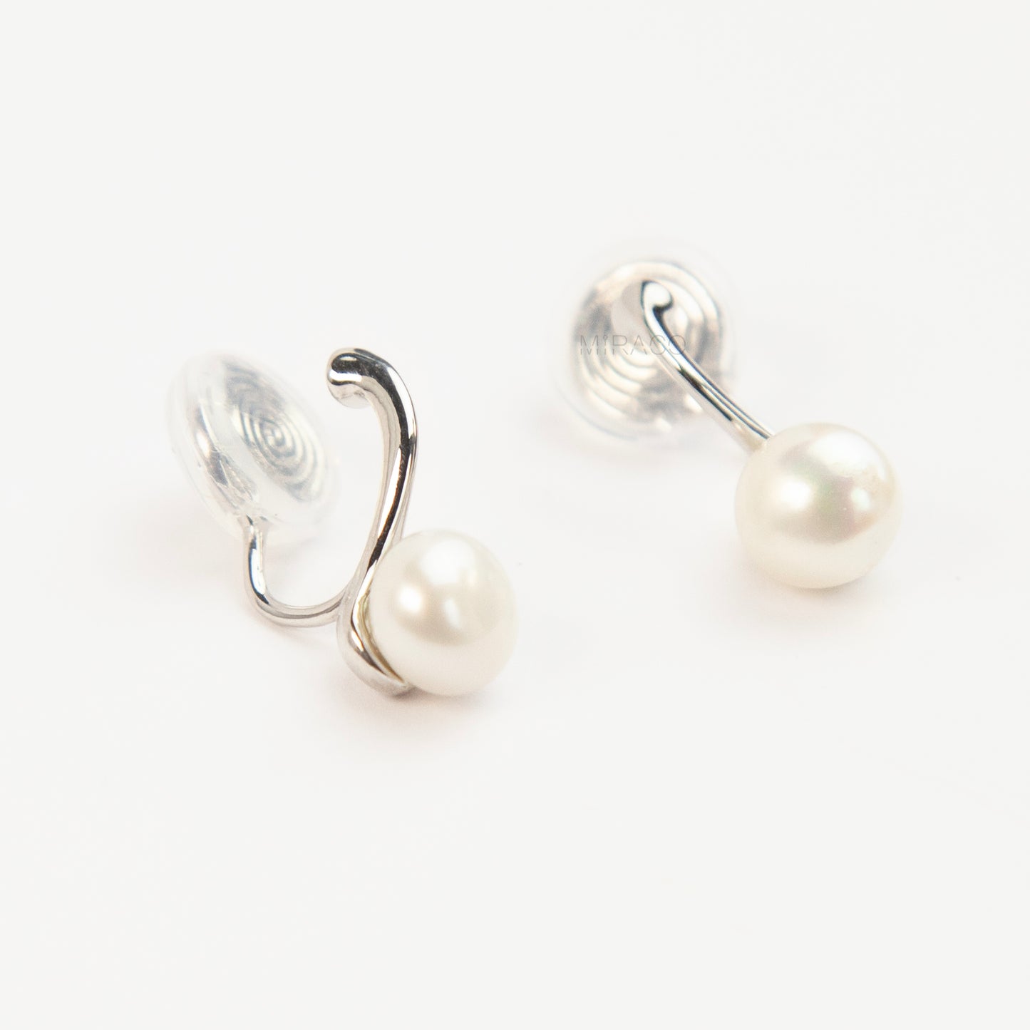 A pair of silver-tone clip-on earrings featuring a single round genuine white pearl dangling from a sleek curved metal bar, equipped with adjustable coil-spring backs