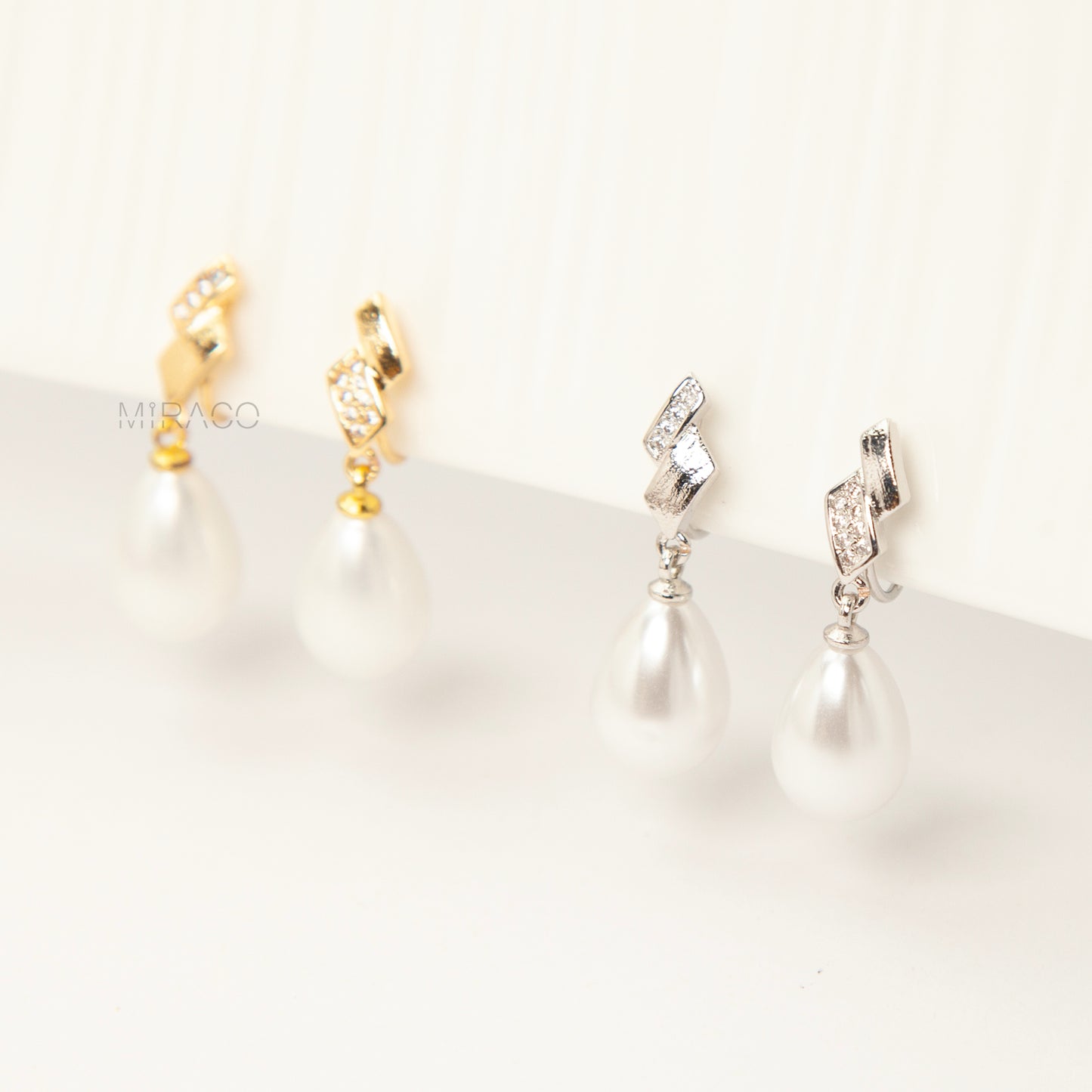 Close-up view of the comfortable coil-back clip mechanism on the gold-tone and silver-tone pearl drop clip-on earrings, showing the secure backing and rhinestone detail.