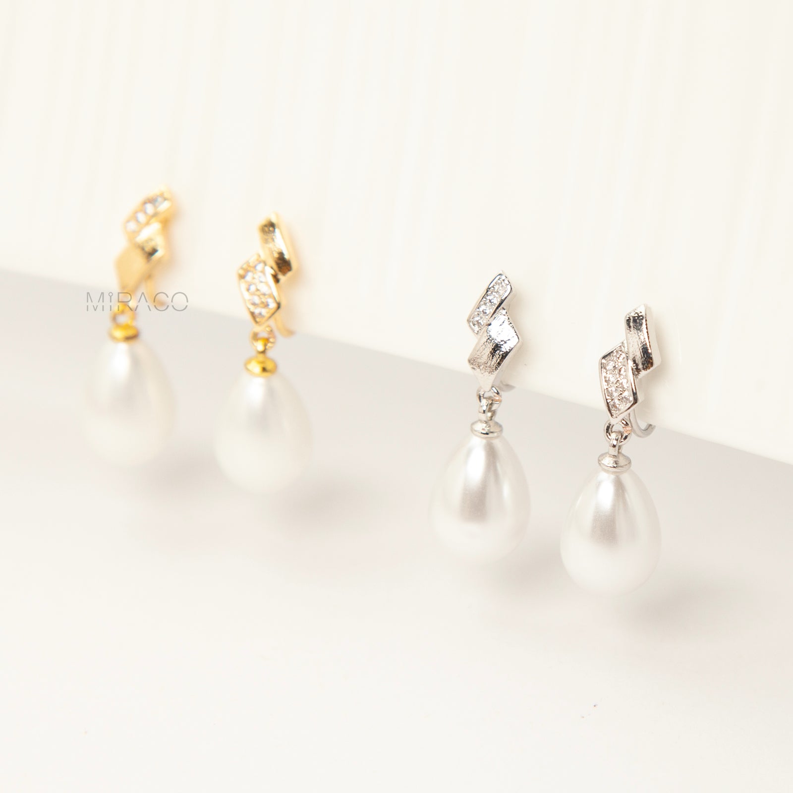 Close-up view of the comfortable coil-back clip mechanism on the gold-tone and silver-tone pearl drop clip-on earrings, showing the secure backing and rhinestone detail.