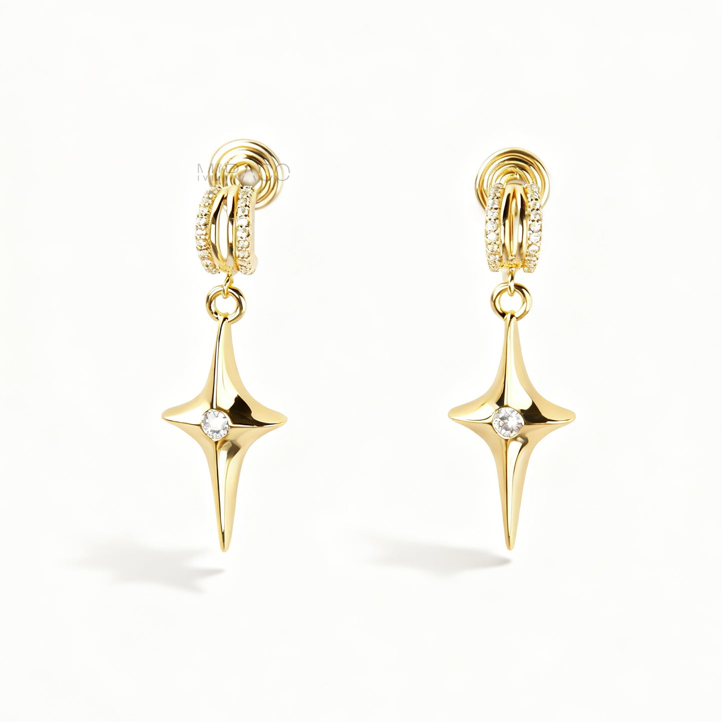A pair of gold-toned dangle clip-on earrings featuring a modern, four-point North Star pendant centered with a clear rhinestone. The top closure is a comfortable coil-back style, partially covered with pave-set rhinestones.