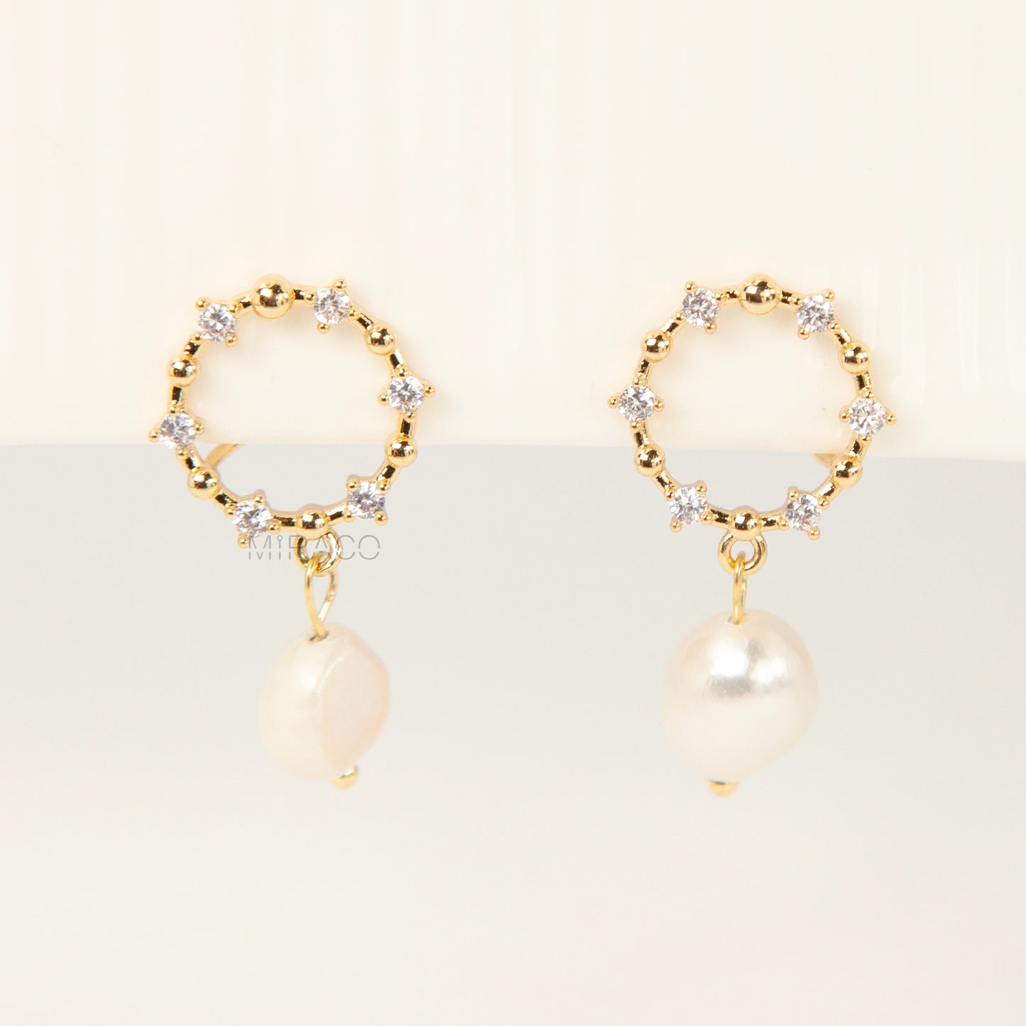 Pair of gold-plated coil back clip-on earrings featuring a wreath shape encrusted with cubic zirconia stones and a dangling white, genuine Freshwater Baroque Pearl.