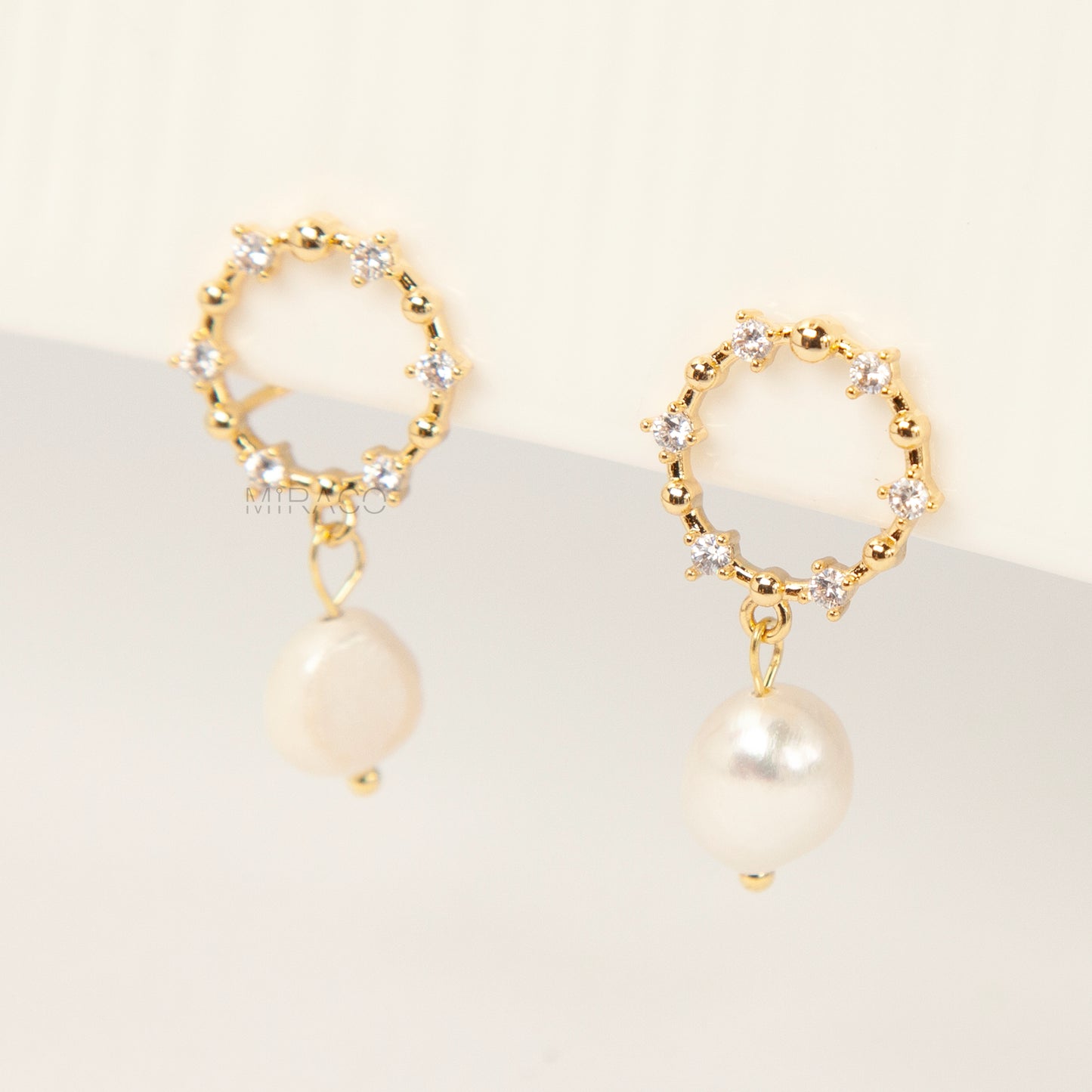 Pair of gold-plated coil back clip-on earrings featuring a wreath shape encrusted with cubic zirconia stones and a dangling white, genuine Freshwater Baroque Pearl.