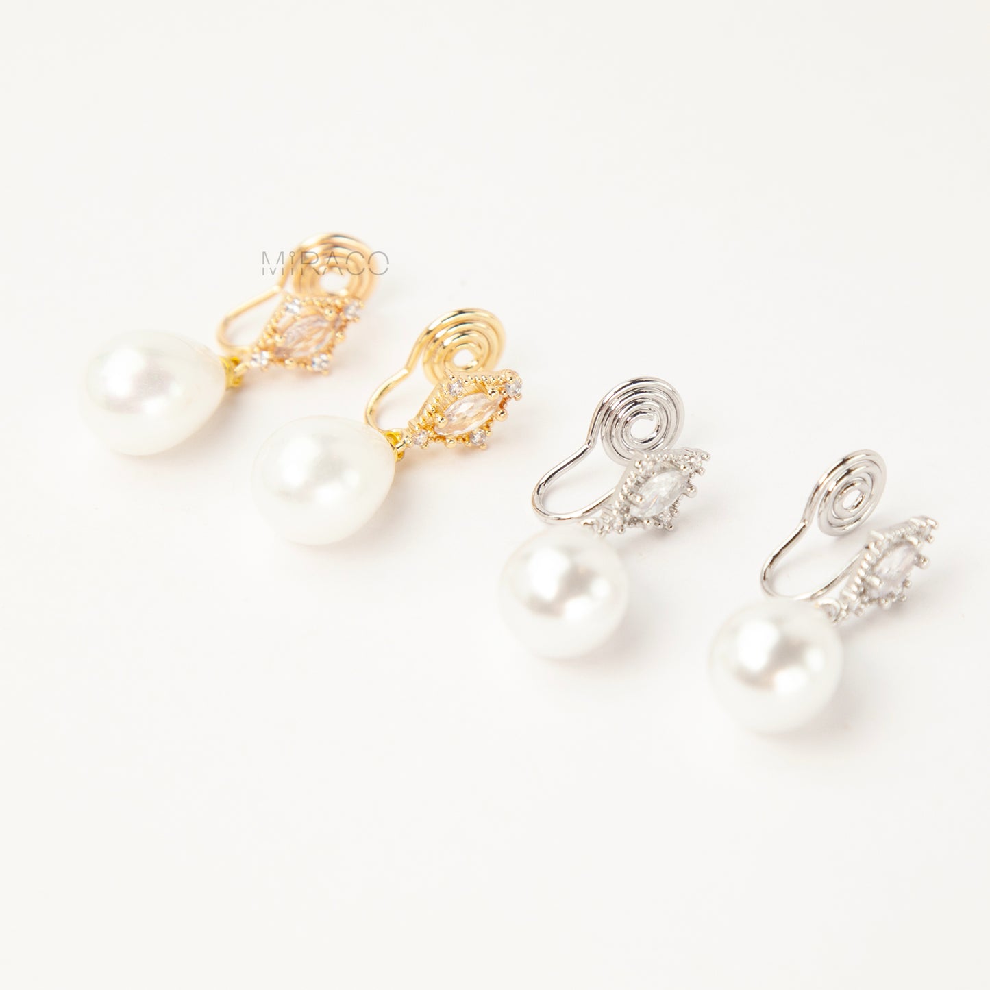 coil back clip-on earrings with a Marquise CZ dangle and a pear-shaped faux pearl drop, shown next to the identical gold-plated version.