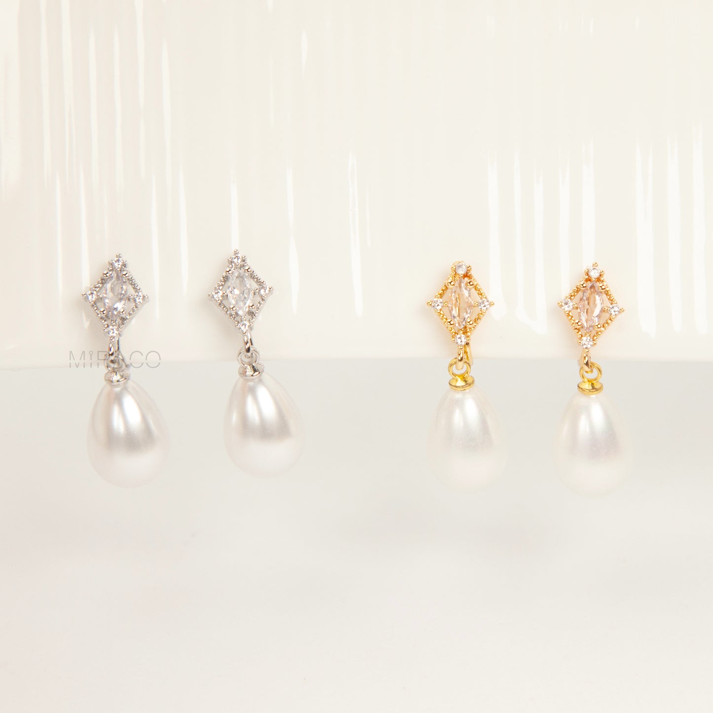 coil back clip-on earrings with a Marquise CZ dangle and a pear-shaped faux pearl drop, shown next to the identical gold-plated version.