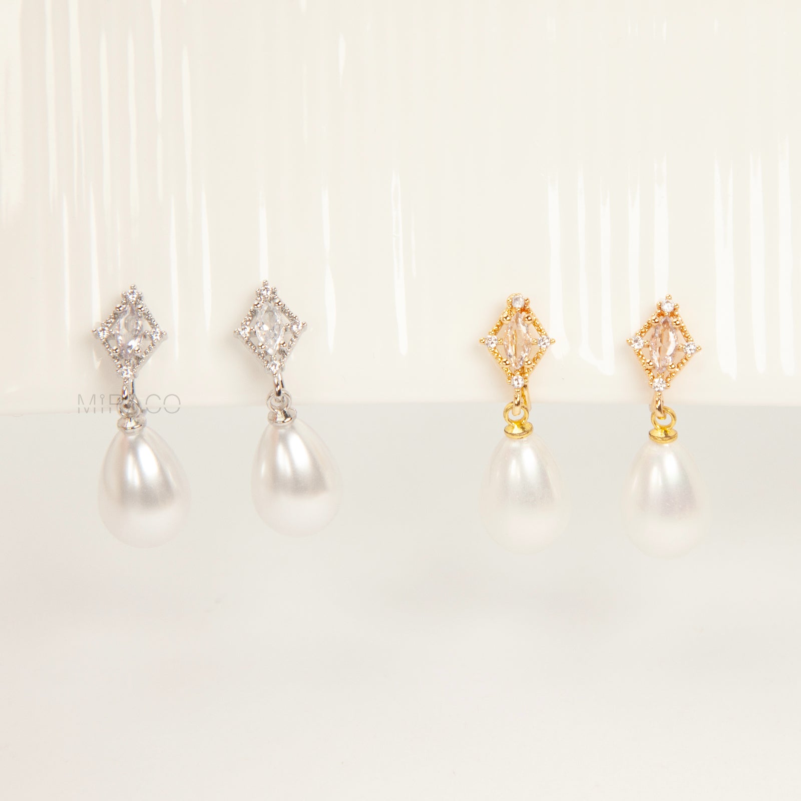 coil back clip-on earrings with a Marquise CZ dangle and a pear-shaped faux pearl drop, shown next to the identical gold-plated version.
