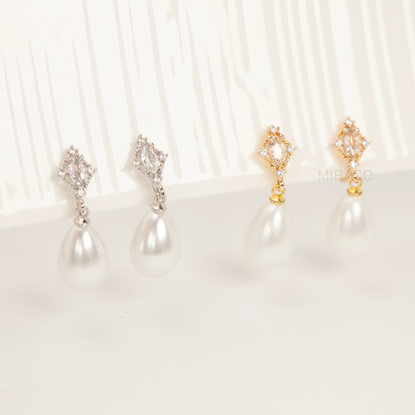 coil back clip-on earrings with a Marquise CZ dangle and a pear-shaped faux pearl drop, shown next to the identical gold-plated version.