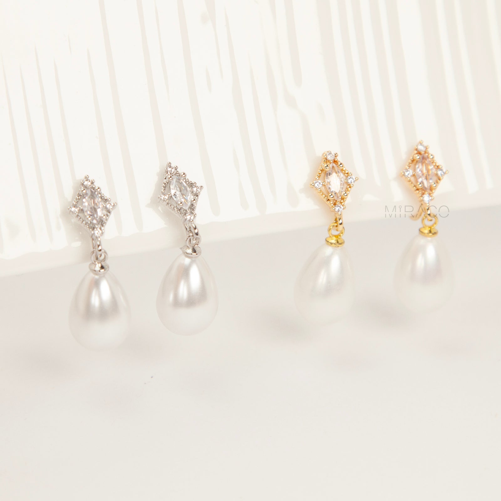 coil back clip-on earrings with a Marquise CZ dangle and a pear-shaped faux pearl drop, shown next to the identical gold-plated version.