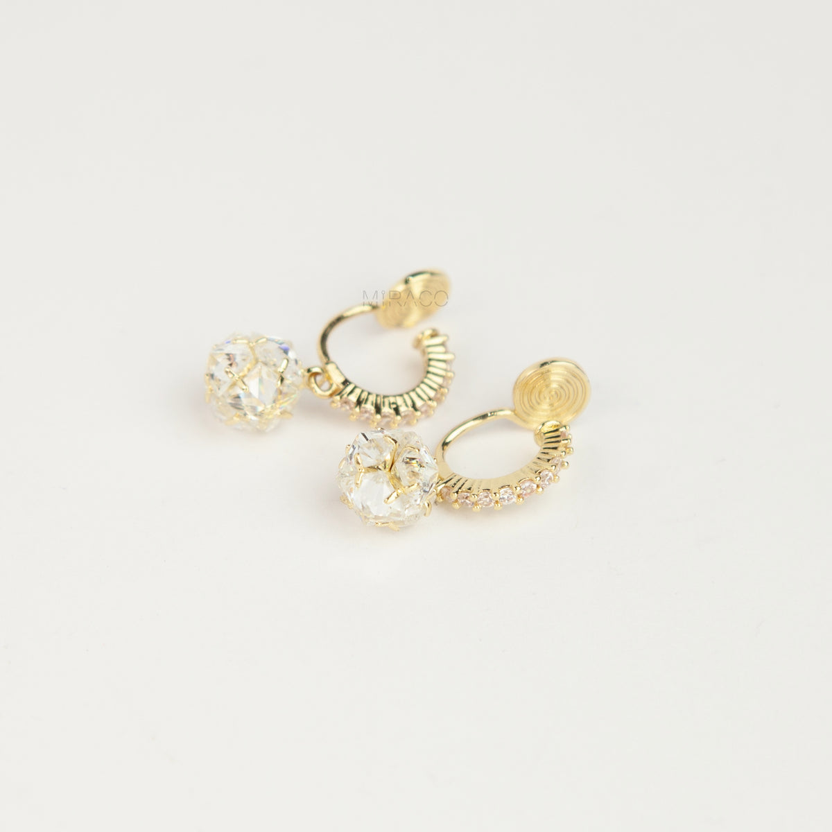 Pair of gold-toned non-pierced clip-on hoop earrings with pavé crystals, clear faceted glass sphere drops, and spiral coil backs with silicone pads.