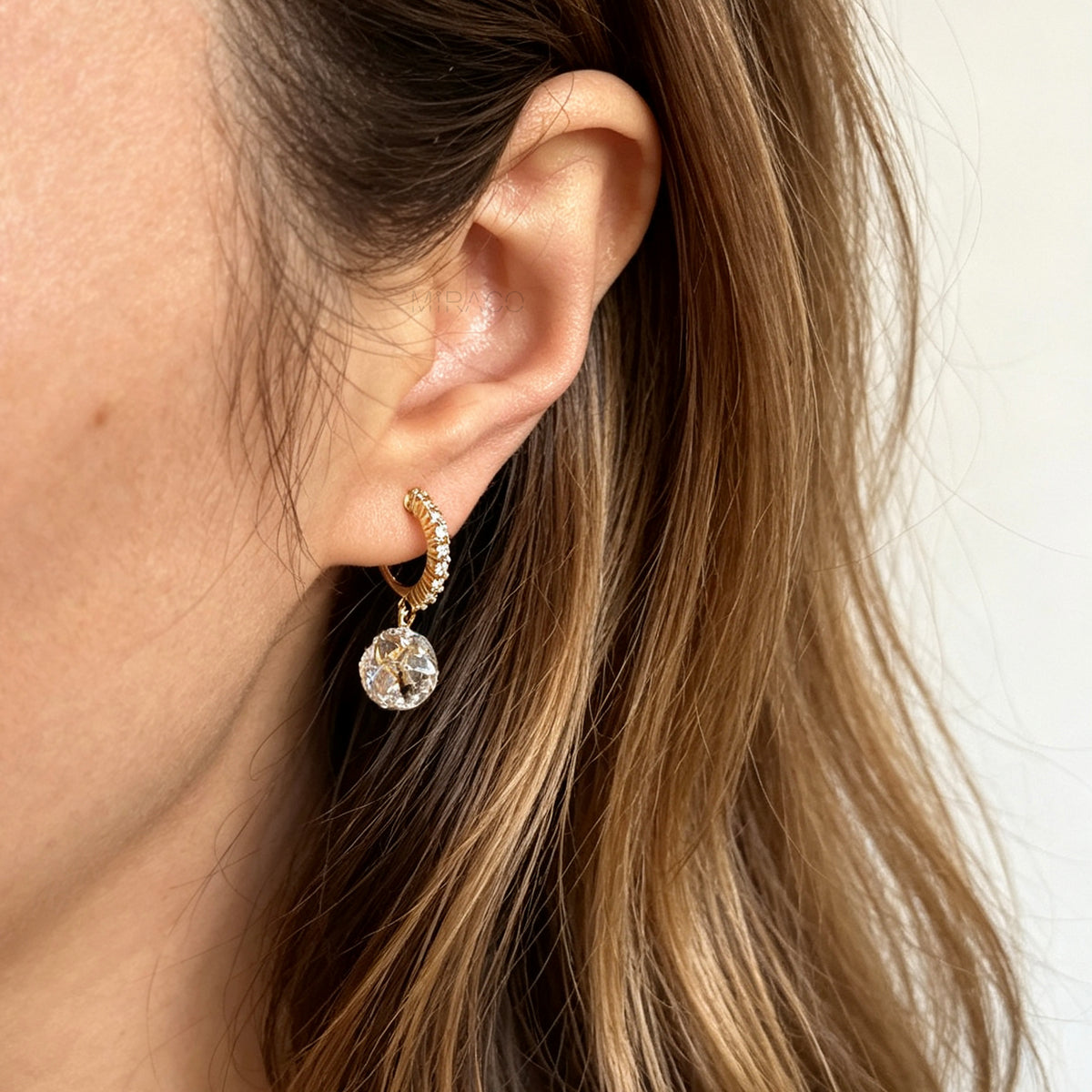 Pair of gold-toned non-pierced clip-on hoop earrings with pavé crystals, clear faceted glass sphere drops, and spiral coil backs with silicone pads.