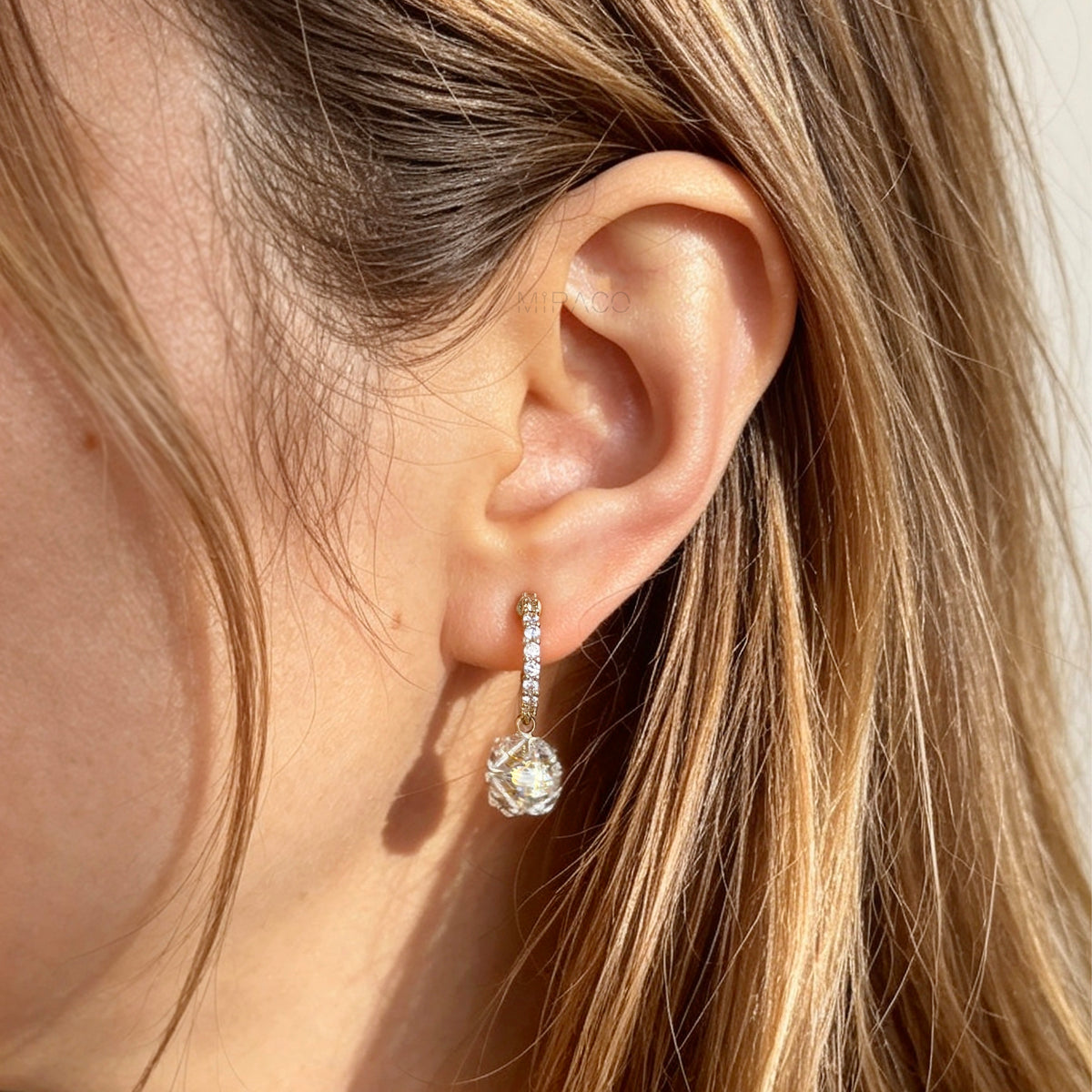 Pair of gold-toned non-pierced clip-on hoop earrings with pavé crystals, clear faceted glass sphere drops, and spiral coil backs with silicone pads.