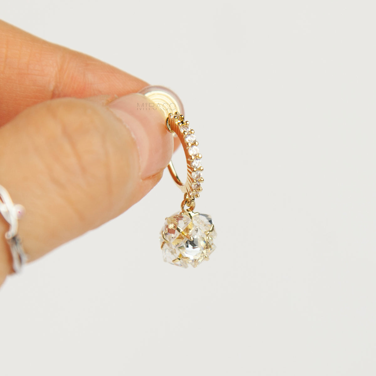Pair of gold-toned non-pierced clip-on hoop earrings with pavé crystals, clear faceted glass sphere drops, and spiral coil backs with silicone pads.