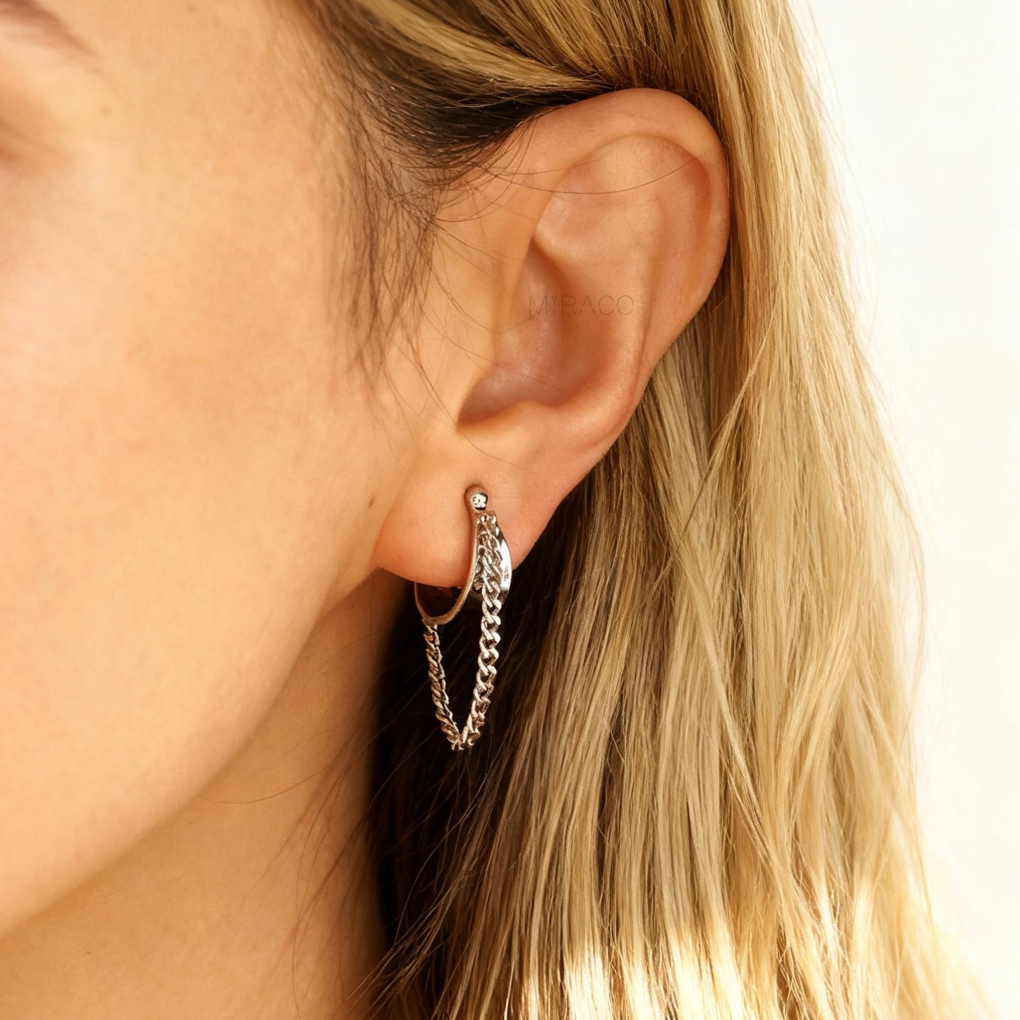 Close-up of a model wearing the silver-tone Chain Hoop Clip-On Earring, showing the comfortable Huggie-style fit on the earlobe.