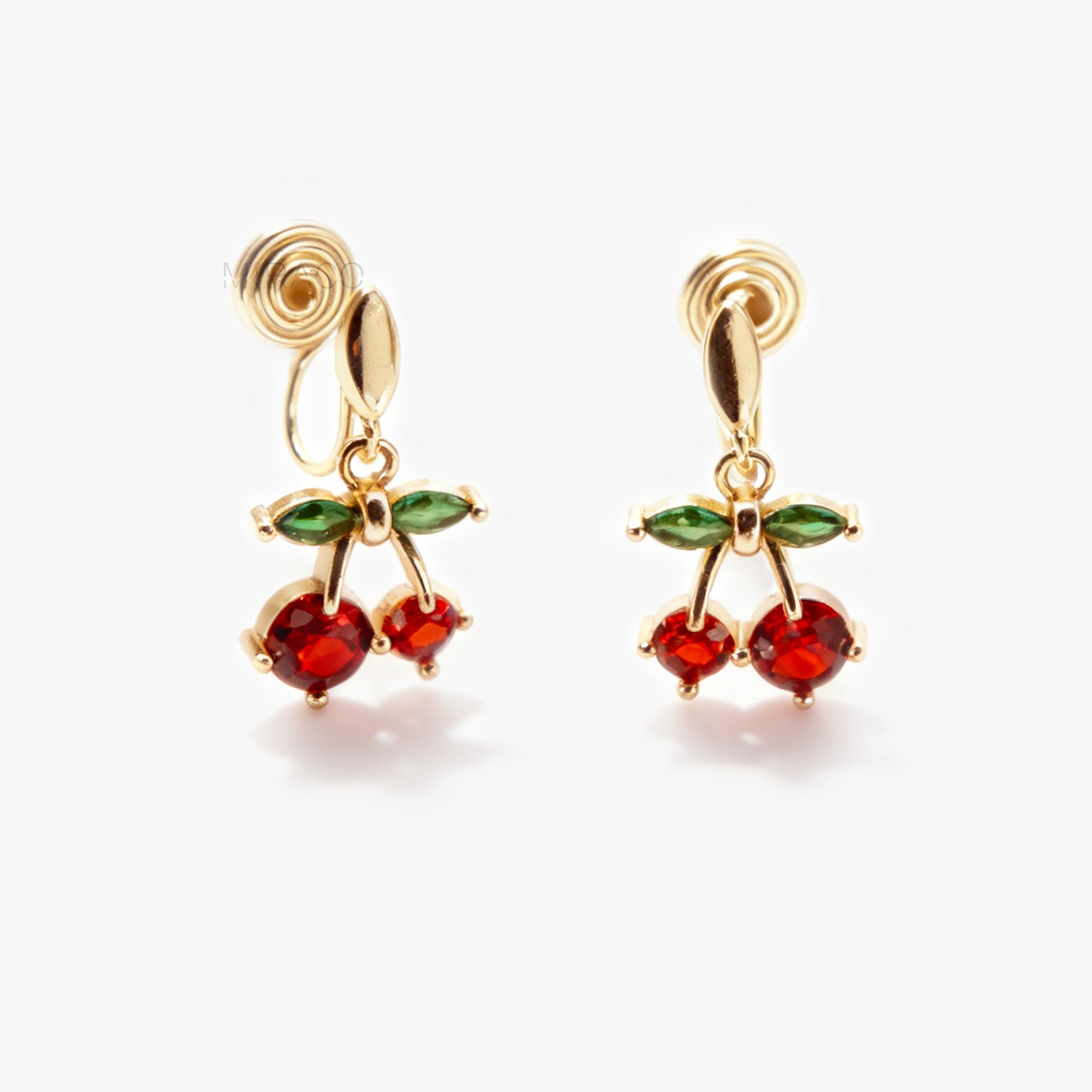 Pair of gold-plated coil back clip-on earrings featuring a double-cherry dangle design. The cherries are made of faceted red cubic zirconia stones with green marquise-cut CZ leaves above them. The back is a round, spiraled coil for comfort.