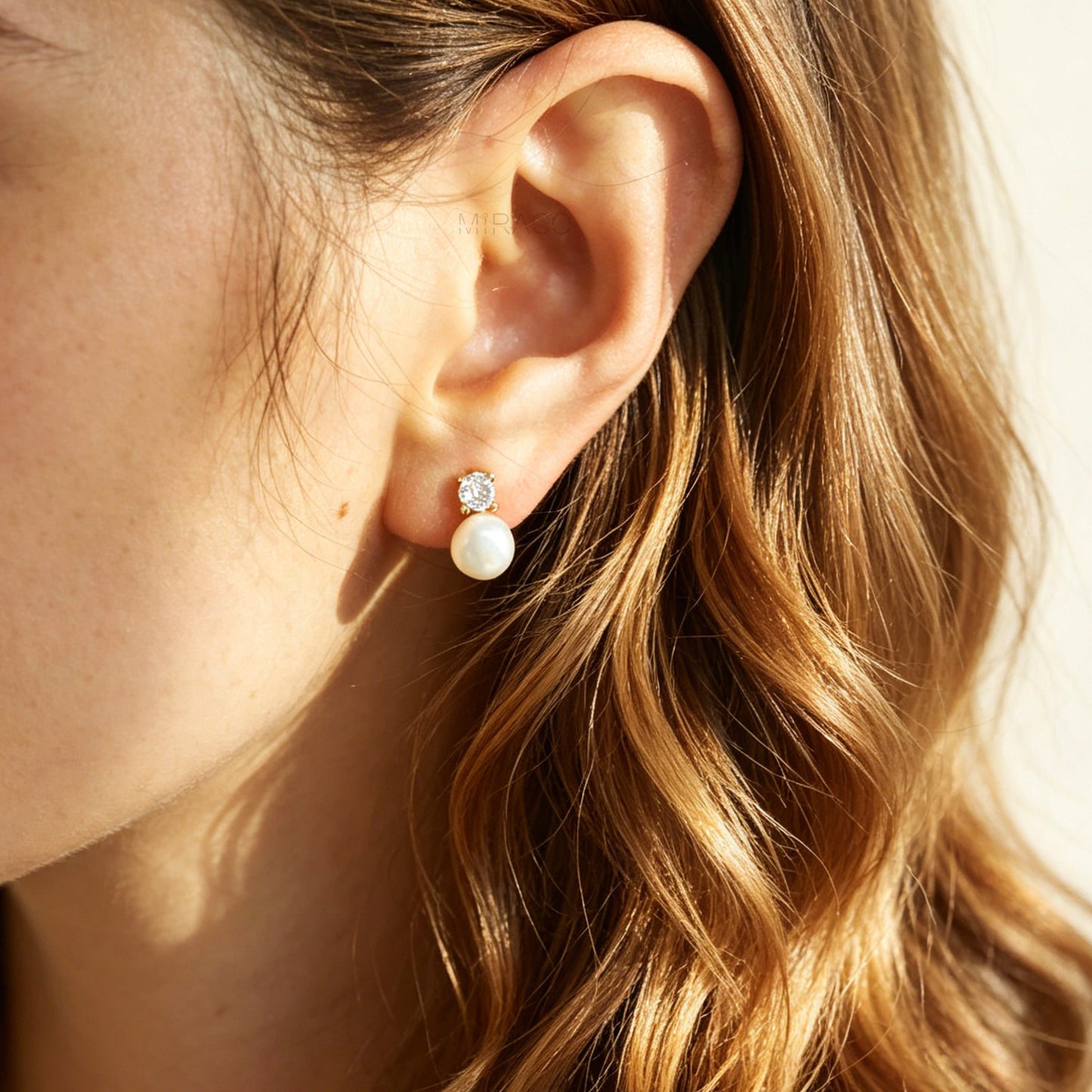 Close-up of an ear wearing a pearl earring with a blurred background