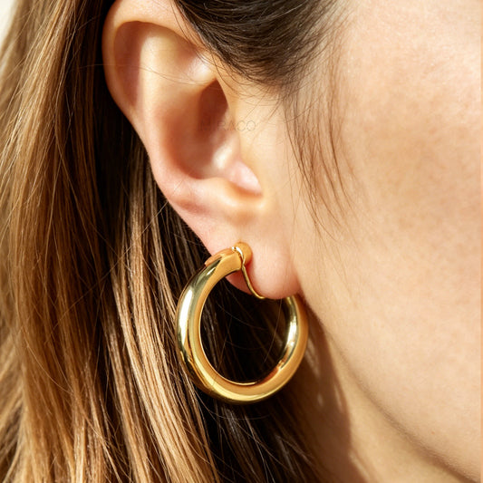 Gold hoop earring worn by a person with brown hair.