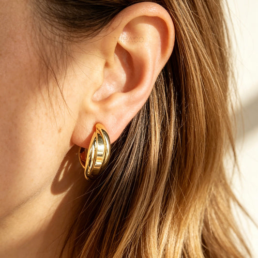 Close-up of a person wearing a gold hoop earring with soft lighting.