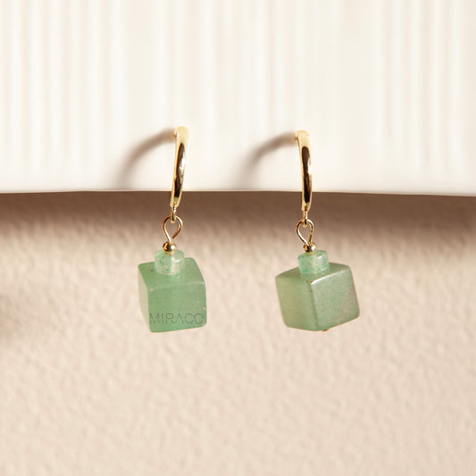 Small Gold Hoops with Square Jade Look Gem | Handmade Coil Clip Earrings for Non-Pierced Ears

A touch of green, a hint of gold – all without the need for pierced ears.

These elegant clip-on earrings feature delicate gold-toned hoops paired with a striking green stone cube dangle. The semi-translucent stone resembles green aventurine, with a gentle, jade-like appearance that catches the light beautifully.

Note:
Each stone is natural and unique, so slight variations in tone and texture may occur – a lovely