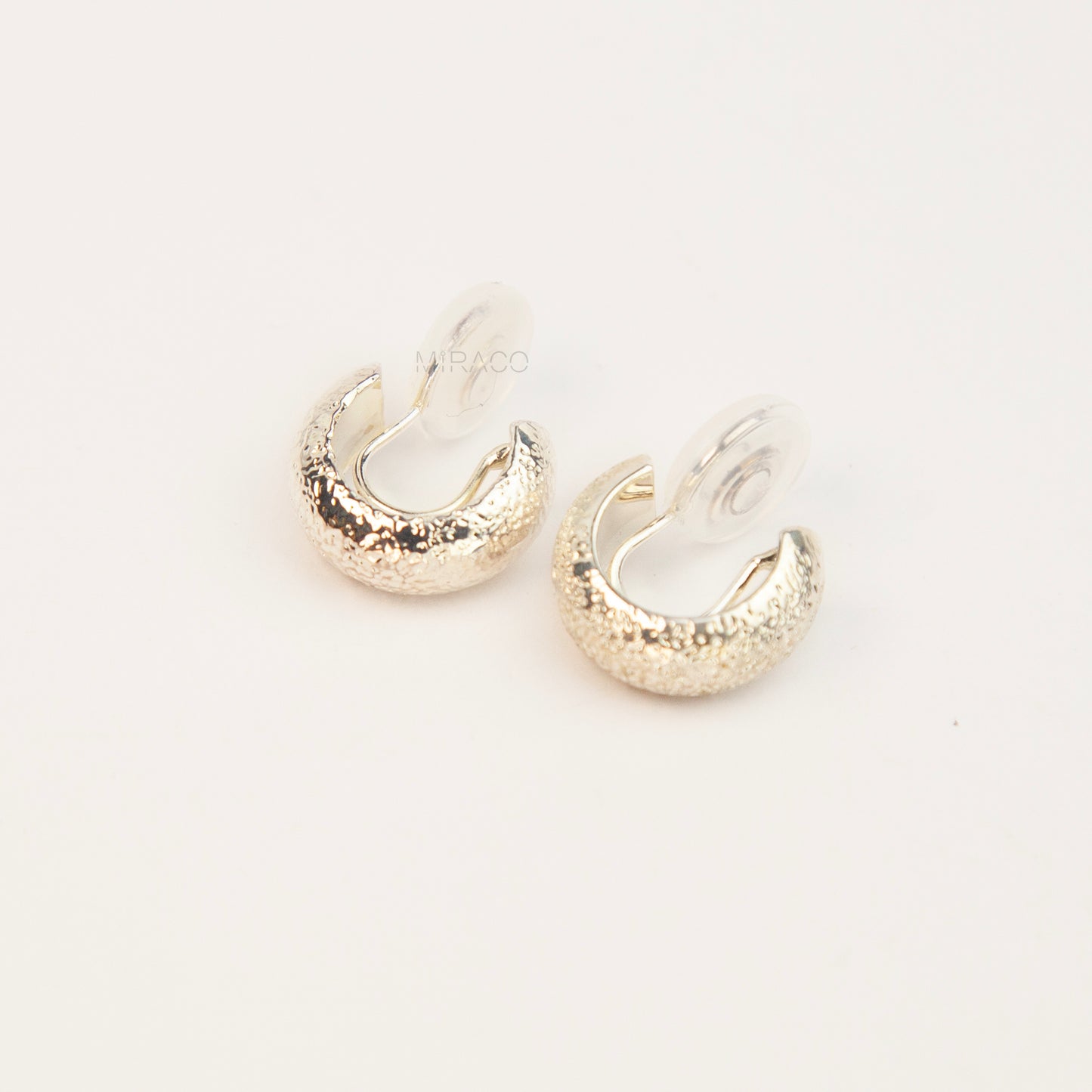 A pair of textured silver hoop earrings, displayed on a clean white background.
