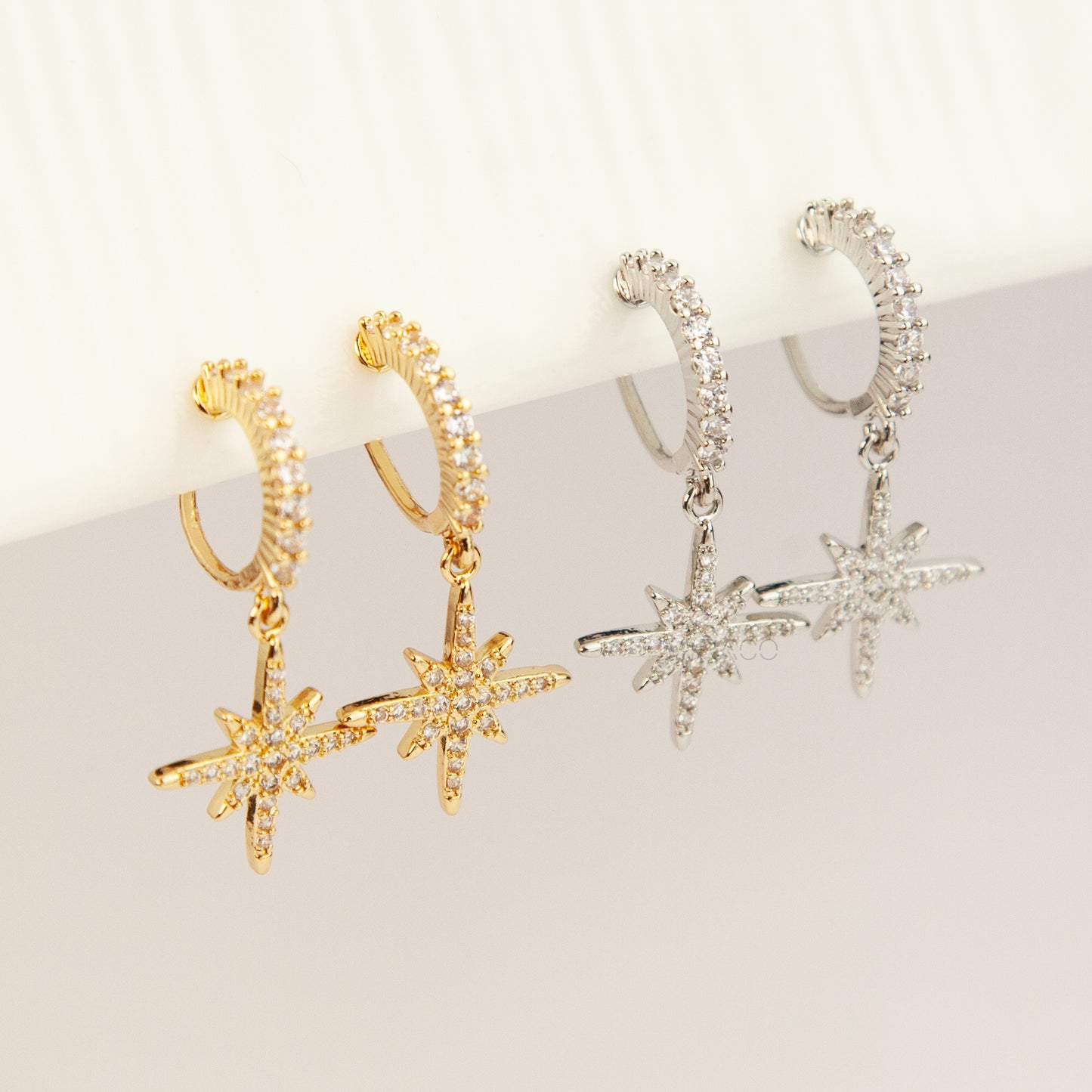 Gold and silver non-pierced clip-on dangle earrings with coil backs, featuring cubic zirconia paved hoops and celestial starburst drops.