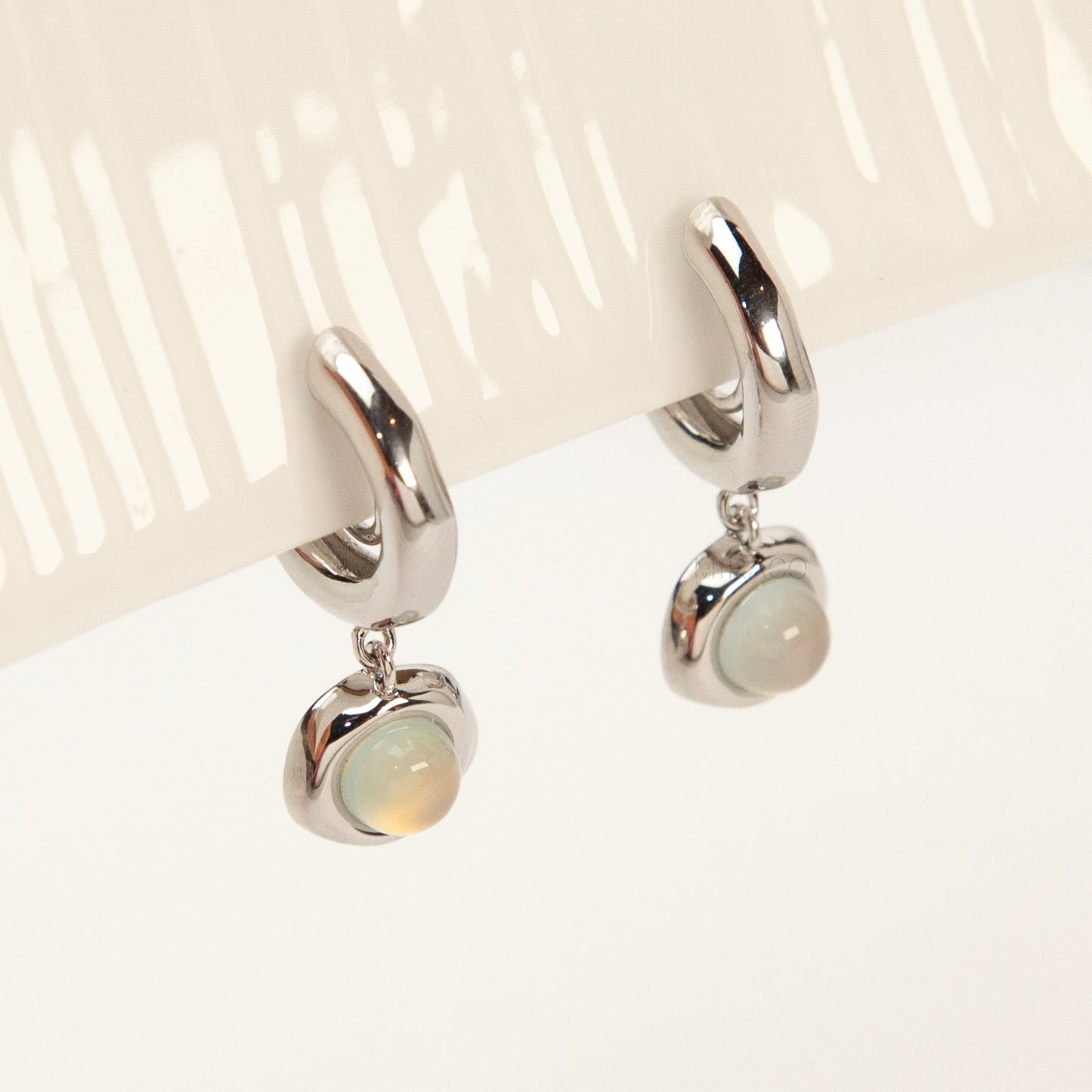Silver opal-style clip-on earrings with curved modern design and coil-back clips for non-pierced ears.
