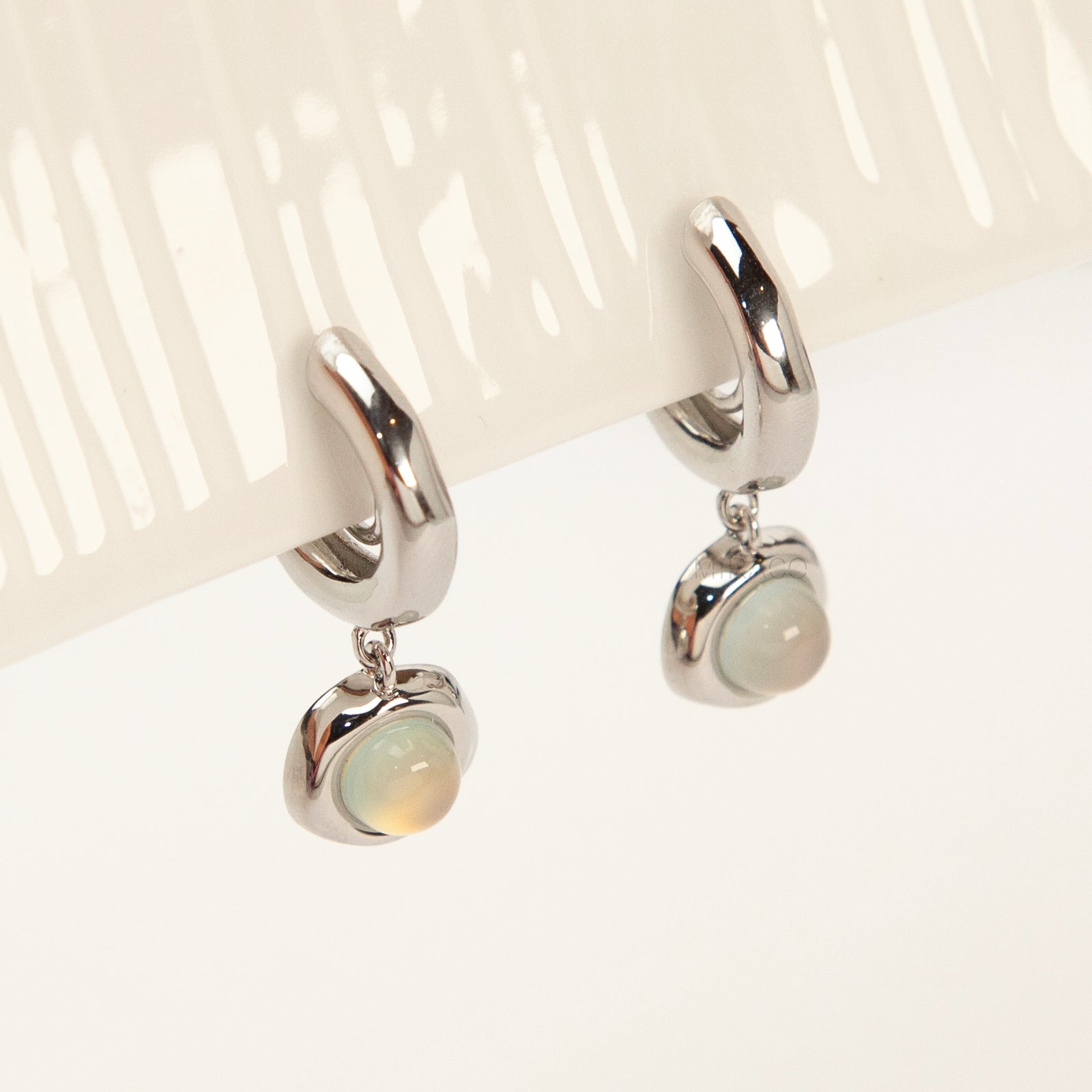 Silver opal-style clip-on earrings with curved modern design and coil-back clips for non-pierced ears.